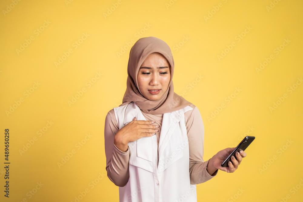 worried muslim woman in hijab using a cell phone worried muslim woman in hijab using a cell phone
