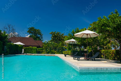 Deckchairs with parasol in tropical resort pool