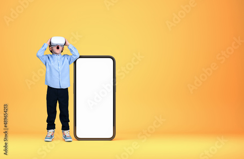 A kid in vr glasses near phone with mockup display on bright bac