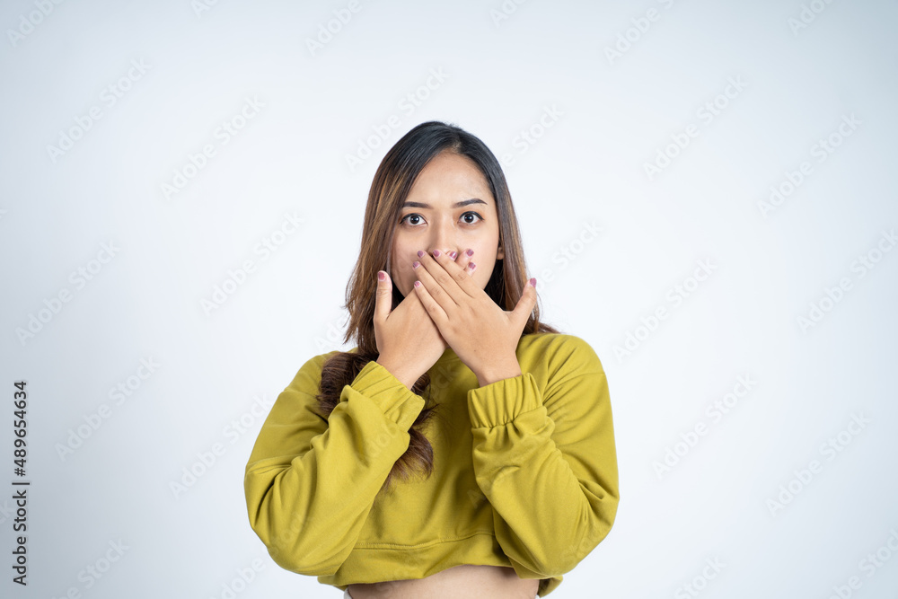 Young woman with shocked expression with hands covering mouth Young woman with shocked expression with hands covering mouth