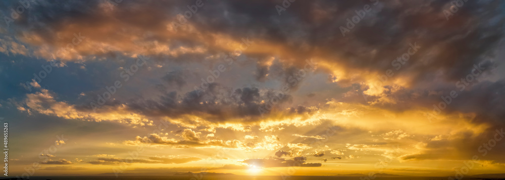A wide panorama of a golden sunset sky over the ocean as background or texture