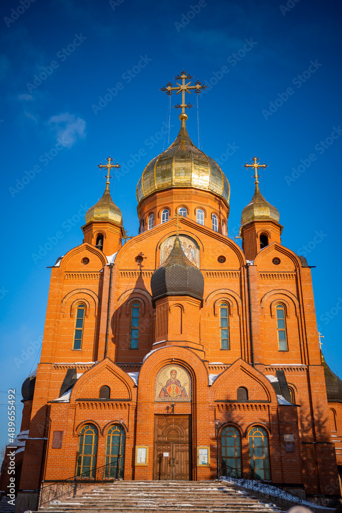Kemerovo, Russia - February 26, 2022: Brick cathedral Orthodox church with crosses under a blue sky in Kemerovo city in Siberia, Russia
