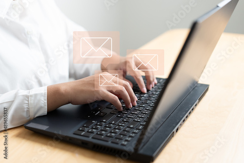 Woman hand typing on keyboard concept of receive or send email icon on working desk with laptop