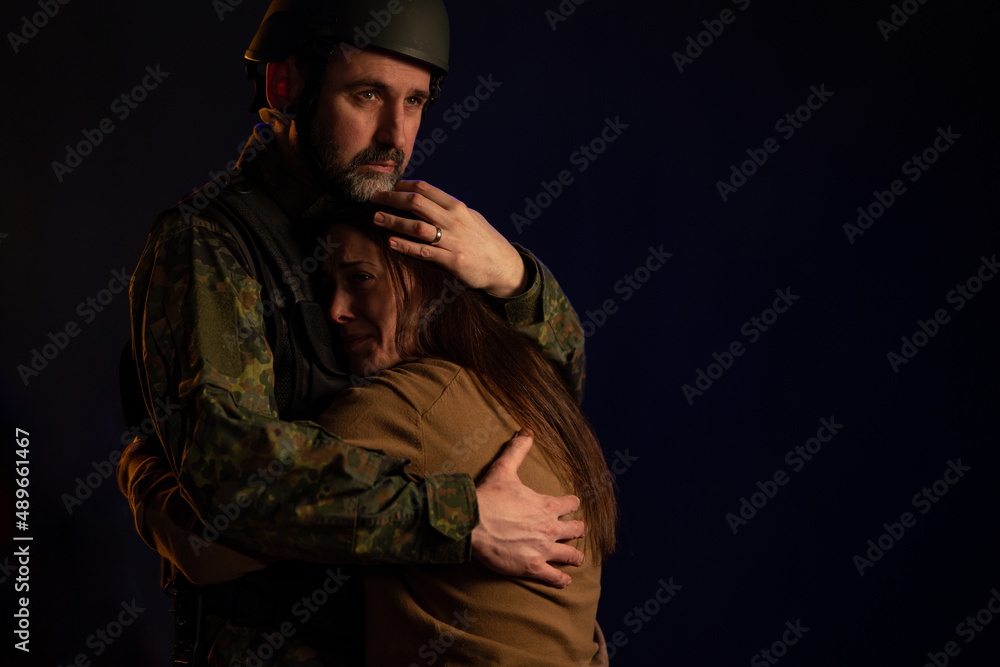 Sad woman hugging her military husband and saying-goodby to him before going to army on black backgound. Sad woman hugging her military husband and saying-goodby to him before going to army on black backgound.