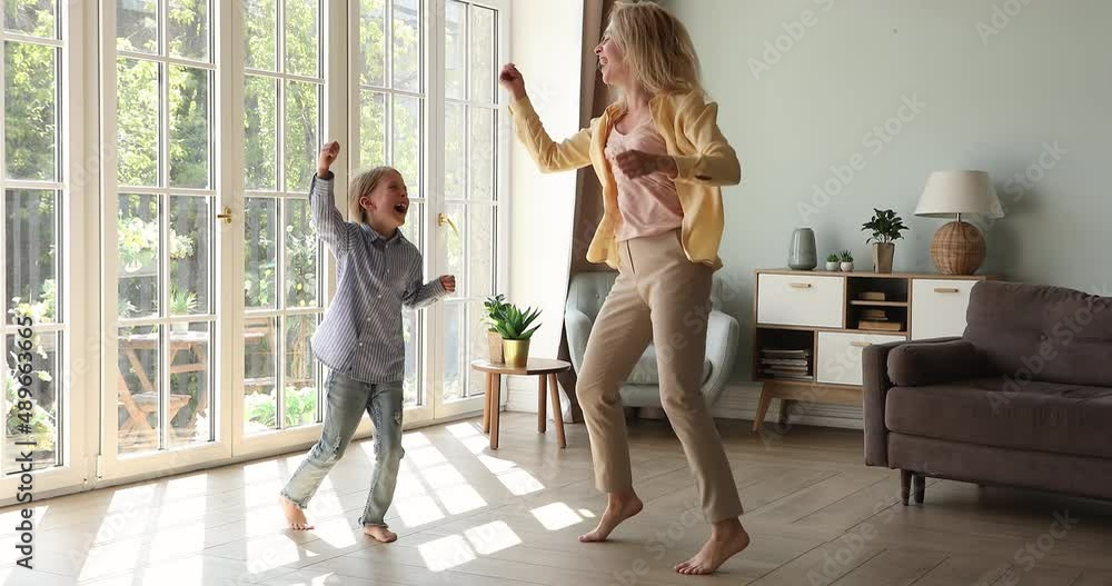 Cheerful happy young woman her little 6s cute daughter listen favourite music having fun dancing barefoot on warm floor in modern spacious living room. Family active weekend leisure and hobby concept Cheerful happy young woman her little 6s cute daughter listen favourite music having fun dancing barefoot on warm floor in modern spacious living room. Family active weekend leisure and hobby concept