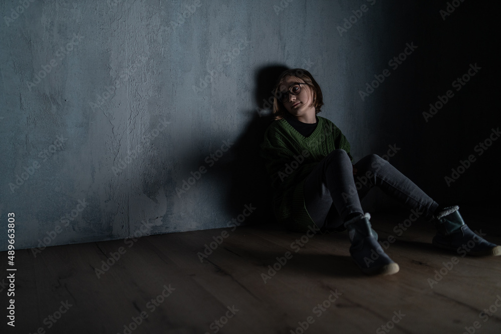 Sad little girl, alone in darkness, sitting and thinking. Sad little girl, alone in darkness, sitting and thinking.