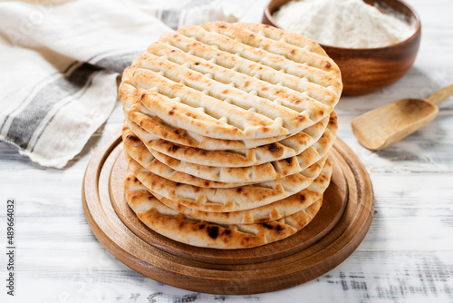 Photos Fresh baked greek pita bread on white wooden background.
