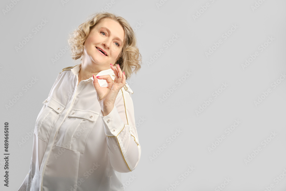 Happy senior woman shows ok gesture. Middle aged woman giving good advice or offer. Happy senior woman shows ok gesture. Middle aged woman giving good advice or offer.