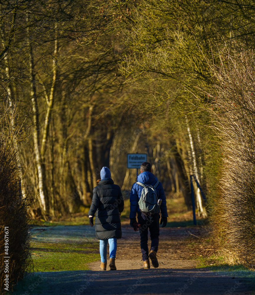 Young couple taking a spring walk in the forest in the Netherlands, with fresh green leafs and lots of warm sunshine