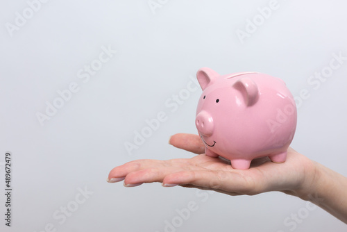 3d pink piggy bank in the beautiful hands of a girl..Close-up photo on a white background.