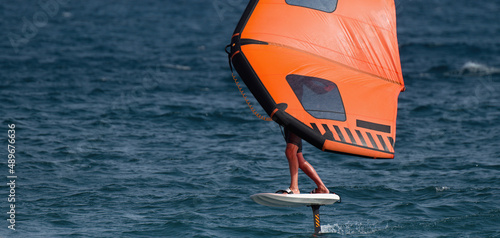 Photography A man is wing foiling using handheld inflatable wings and hydrofoil surfboards i