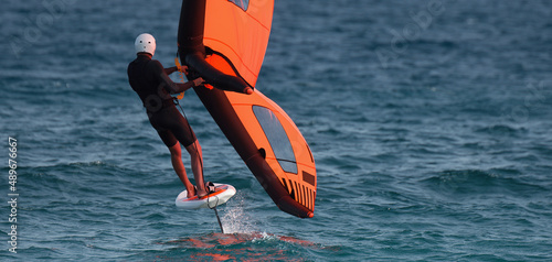 Konstfotografi A man is wing foiling using handheld inflatable wings and hydrofoil surfboards i