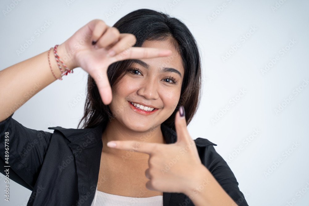 young woman looking from between fingers forming a frame young woman looking from between fingers forming a frame