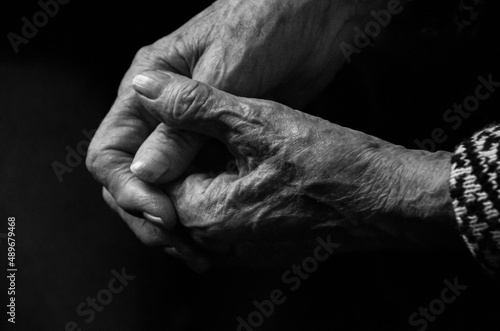 Hands of an elderly woman on a black background, the concept of old age. Black and white photo.