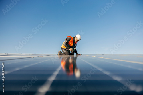 Worker kneeling and sets solar panel. photo
