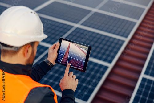 A worker taking a picture of installed solar panels. photo