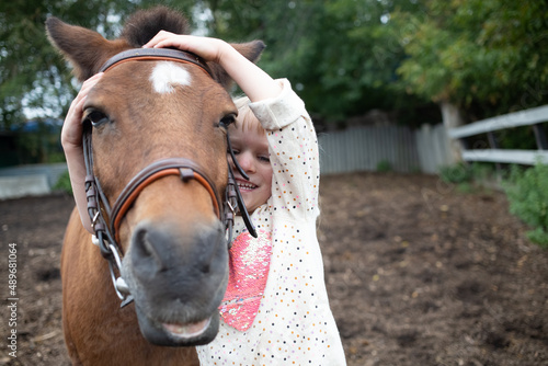 girl hugging pony horse muzzle at ranch © Maria