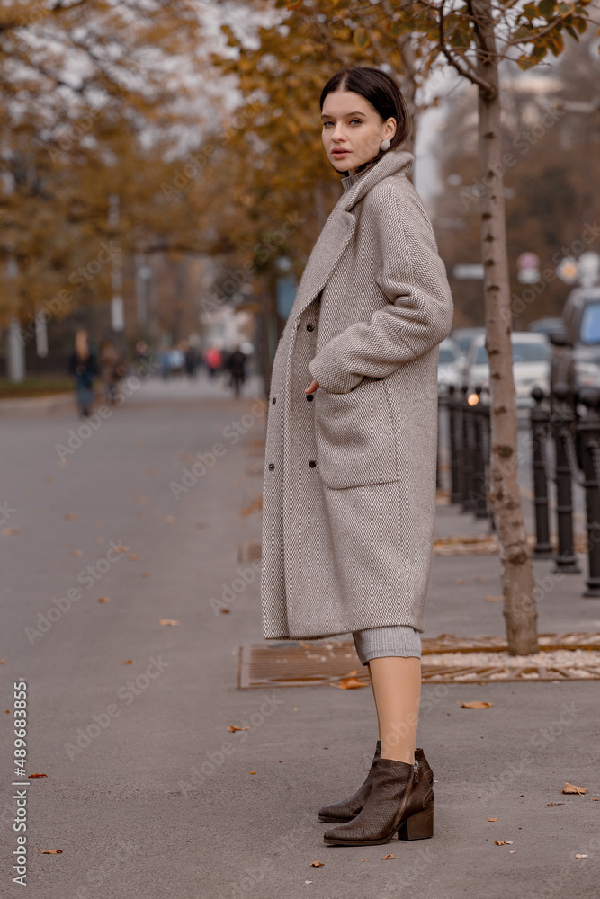 Fototapeta premium Fashionable girl walking down the street in a European city in a stylish coat