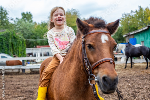 happy little girl riding pony horse bareback and laugh © Maria
