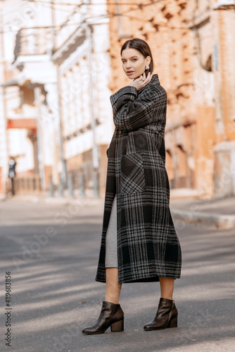 Fashionable girl walking down the street in a European city in a stylish coat