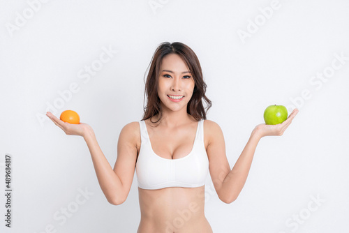 Beautiful asian young woman healthy food wearing white underwear holding green apple with healthy food isolated on a white background.
