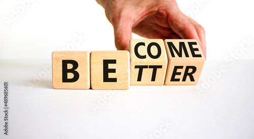 Become better symbol. Businessman turns wooden cubes and changes the concept word Better to Become. Beautiful white table white background. Business become better concept. Copy space.