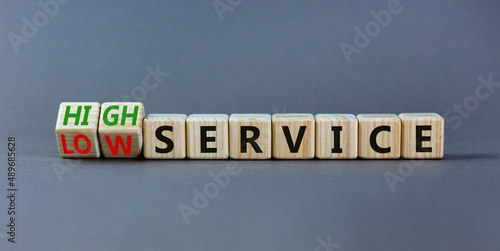 Low or high service symbol. Turned wooden cubes and changed words low service to high service. Beautiful grey table grey background. Business low or high service concept, copy space.