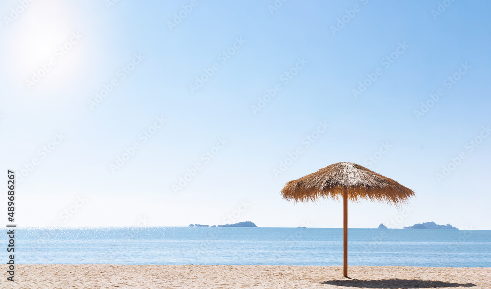 Calm sea beach and thatched roof umbrella.