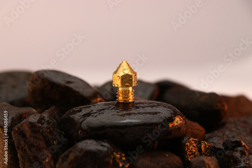 3D printer brass nozzle on a wet stone, Spare parts for 3d printer machine photo