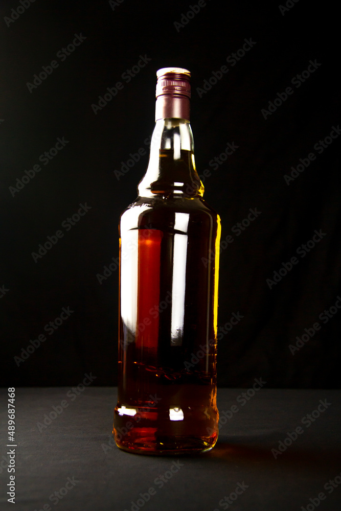 A bottle of amber whiskey on a black background in a bar