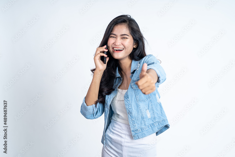 Fototapeta premium Young asian woman making a call using a mobile phone with thumbs up