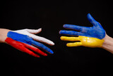 The concept of friendship of peoples between Russia and Ukraine. War between countries, political differences. Flags on hand photo on black background.