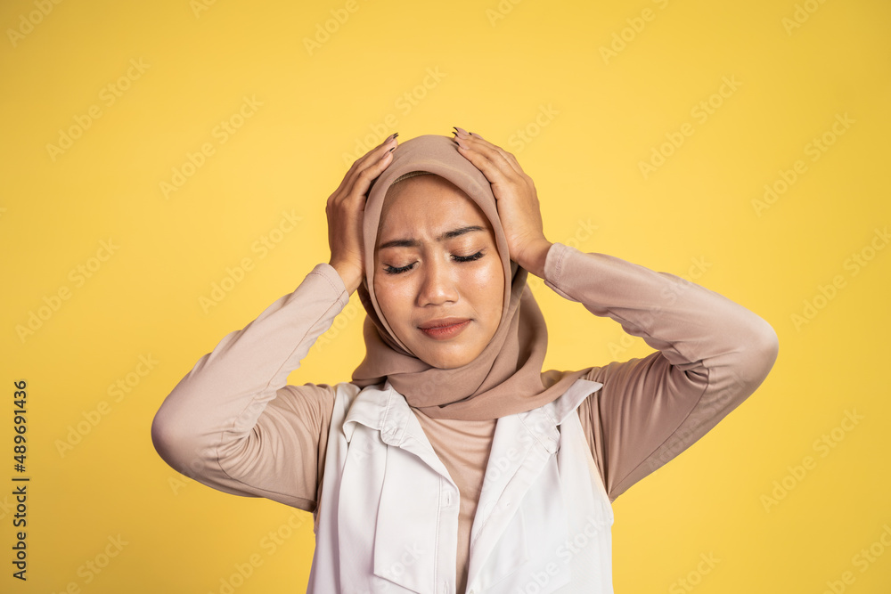 Asian woman in hijab holding head with headache Asian woman in hijab holding head with headache