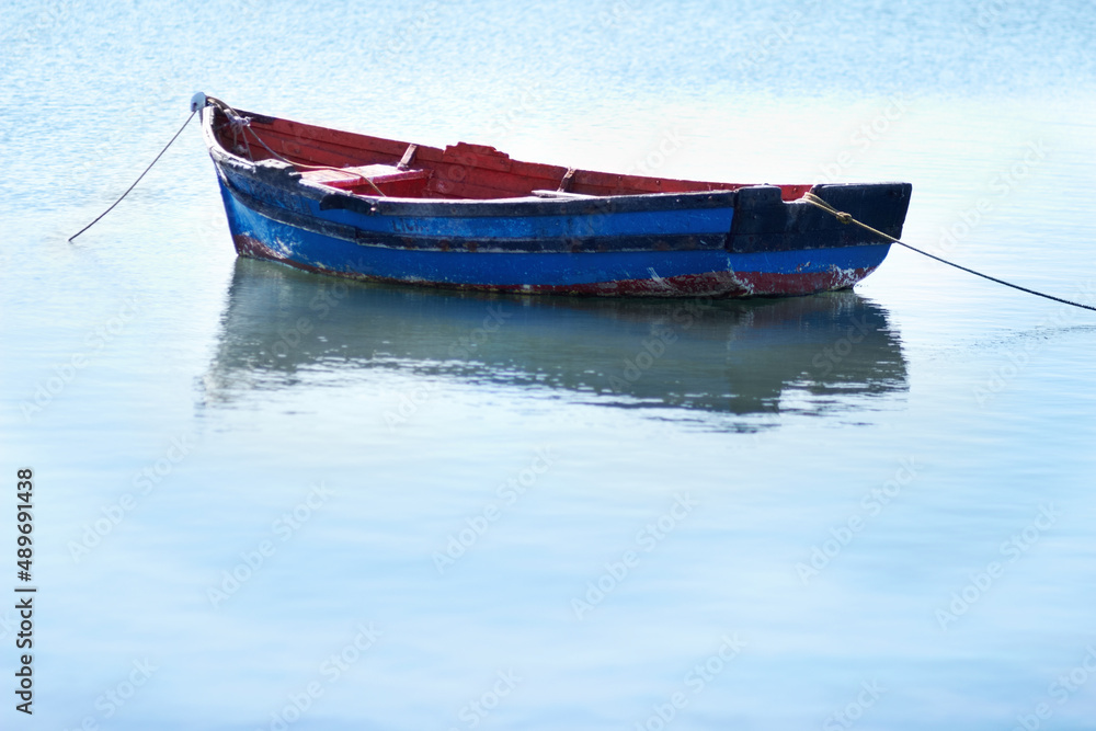 Not a breath of wind today. Shot of an empty fishing boat floating on calm waters.
