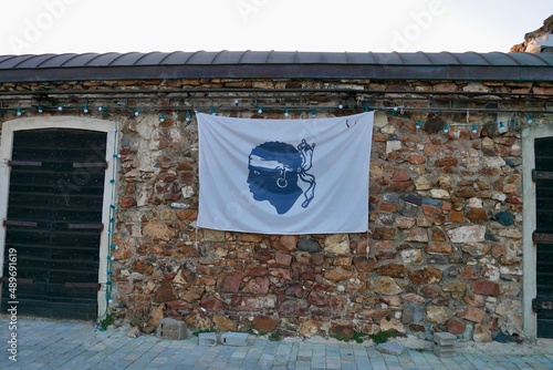 Flag of Corsica, the famous Moors's Head known as Bandera di Corsica, hanging on wall of traditional stone house. Corsica, France. photo