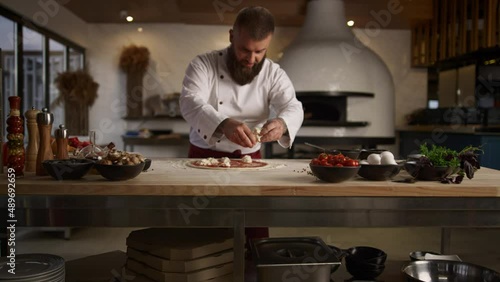 Pizza chef man cooking italian dinner recipe in kitchen. Baker put mozzarella. photo