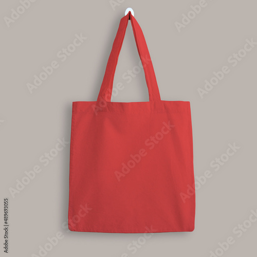 Red blank cotton eco tote bag, design mockup. Shopping bag hanging on wall photo