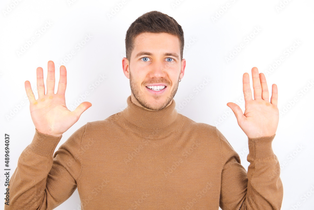 young caucasian man wearing grey turtleneck over white background showing and pointing up with fingers number ten while smiling confident and happy. young caucasian man wearing grey turtleneck over white background showing and pointing up with fingers number ten while smiling confident and happy.