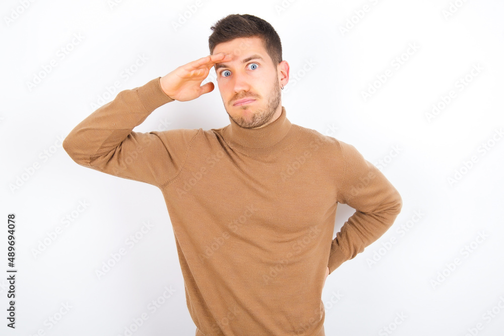 young caucasian man wearing grey turtleneck over white background having problems, worried and stressed holds hand on forehead. young caucasian man wearing grey turtleneck over white background having problems, worried and stressed holds hand on forehead.