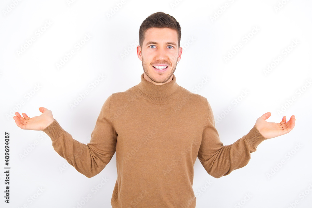 Cheerful cheery optimistic young caucasian man wearing grey turtleneck over white background holding two palms copy space Cheerful cheery optimistic young caucasian man wearing grey turtleneck over white background holding two palms copy space