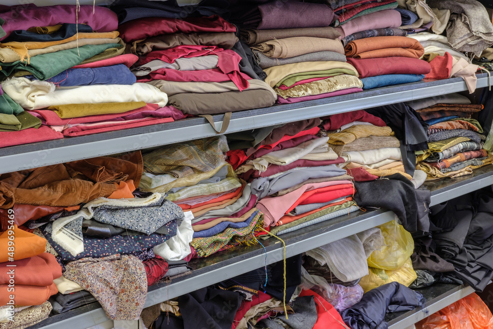 Multicolored various clothes stacked in piles on a shelf in a atelier Multicolored various clothes stacked in piles on a shelf in a atelier