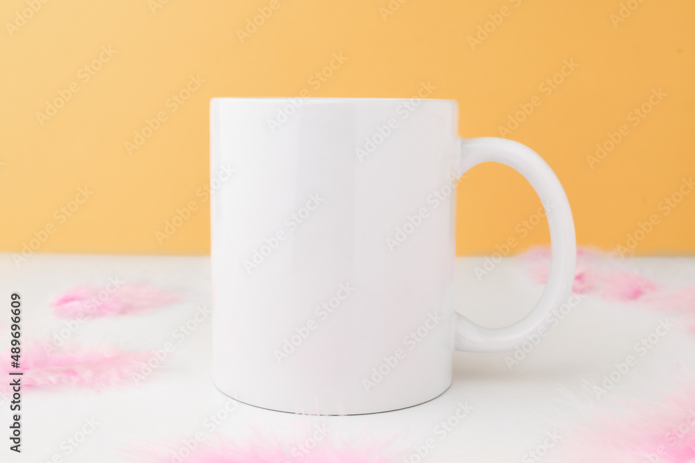 White empty mug for design and logo on an orange background with Easter decor. Mockup with copy space. White empty mug for design and logo on an orange background with Easter decor. Mockup with copy space.