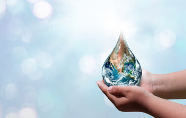 World water day. A globe in the shape of a drop of water falling onto the boy's hand on blue sea background. Elements of this image furnished by NASA .