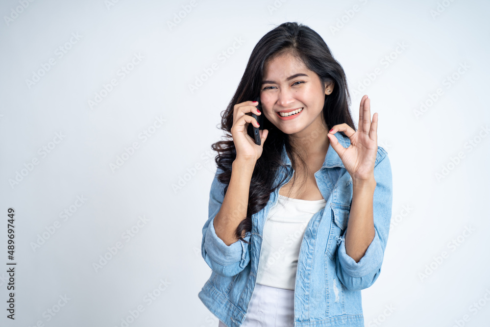 Young woman making a call with ok hand gesture Young woman making a call with ok hand gesture