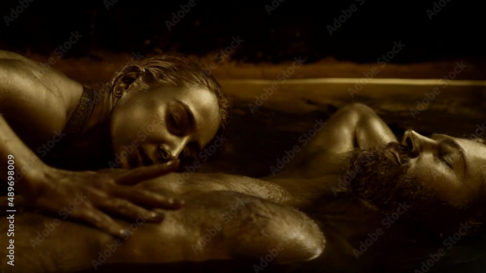 sexy lady is seducing sleeping handsome man, lovers are lying in golden water sexy lady is seducing sleeping handsome man, lovers are lying in golden water