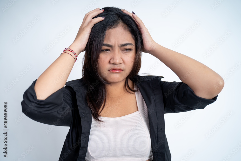 Fototapeta premium Young woman holding head while confused by situation