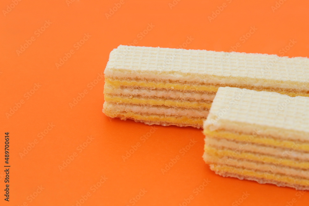 Fototapeta premium Two waffles lie on an orange background