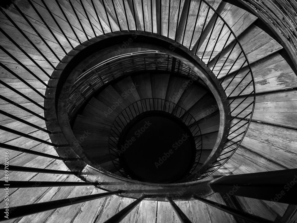 Spiral staircase. Black and white image of wooden and iron spiral stairway down to the dark.