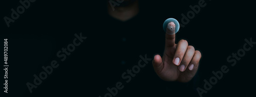 Blue fingerprint scan icon on virtual screen while finger scanning for security access with biometrics identification on dark. Cyber security, privacy data protection technology for business. photo