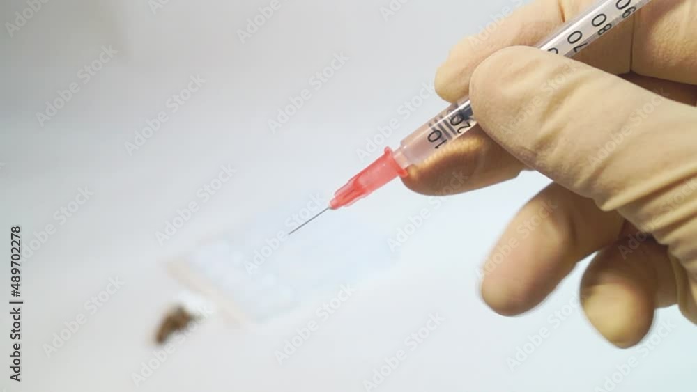 The cap is removed from the insulin syringe with hands in medical gloves The cap is removed from the insulin syringe with hands in medical gloves
